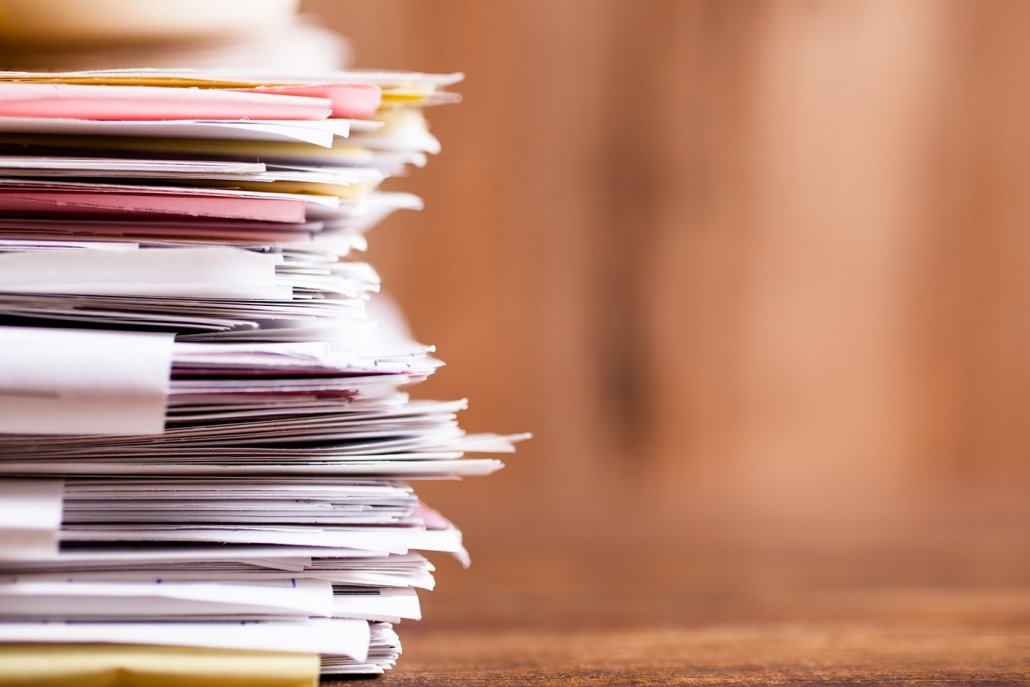 jobmesse-nachbereitung-tipps Papierstapel vor unscharfem Hintergrund